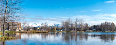 Panorama manzaralı göl manzaralı apartman ve yazlık ev, Spenard Gölü 'nde yüzen uçaklar Chugach Dağı Anchorage, AK. Kamu malı ve dünyanın en yoğun deniz uçağı üssü