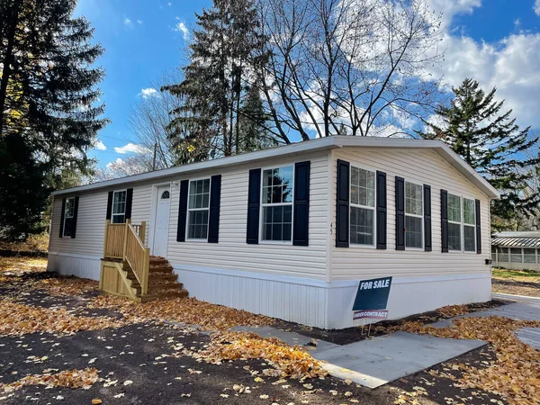 stock image Brand new prefab mobile home with for sale yard sign post, colorful fall foliage near Rochester, New York. Prefab construction manufactured modular house wood step, concrete sidewalk parking lot