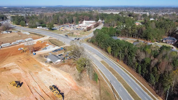 stock image Local church near large construction project with heavy machine, cement pipes, debris pile and earthmoving works for raft foundation near Camp Branch Rd in Buford, Georgia, USA. Aerial warehouse