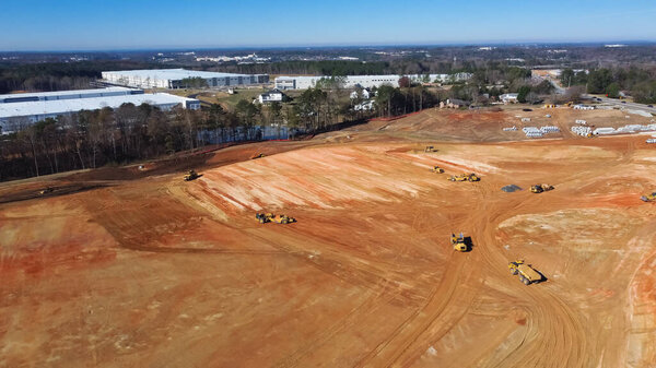 Вид с воздуха большой строительный проект рядом с завершенными коммерческими или промышленными складскими зданиями рядом с Camp Branch Rd в Бьюфорде, Джорджия, США. Куча фундамента для землеройных заводов
