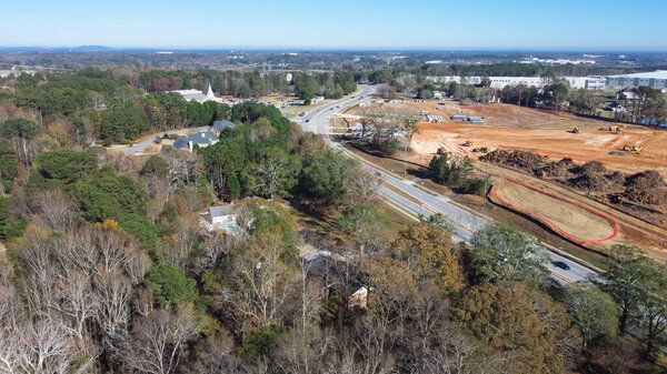 Очаровательный район с маленькой церковью рядом с крупным строительным проектом с земляными работами, тяжелой промышленной техникой в Кэмп-Бранч-Рд в Буфорде, Джорджия, США. Куча воздушного мусора