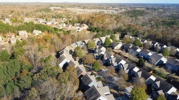 Residential neighborhood master-planned community and subdivision sprawl in woodland area with tall mature trees and Chestnut Mountain background. Aerial view two story house suburbs Atlanta, GA, US