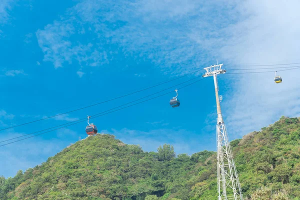Upward view of gondola lift support tower with cable cars and mountain background in Vung Tau, Vietnam. Steel and tubular framework pylon for aerial tramway to Ho May Park tourist attraction