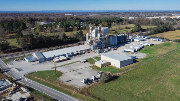 Top view industrial zone in Flowery Branch, Georgia with large animal nutrition premix plant, warehouses and Chestnut Mountain background. Silos, tanker, shipping containers, heavy feed machinery