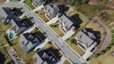 Row of two story houses with swimming pool, large backyard and well trimmed front yard in upscale residential neighborhood outside Atlanta, Georgia, US. Aerial suburban home shingle roof front garage