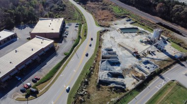 Ready-mixed concrete batching plant near strips mall highway in Flowery Branch, Georgia, USA. Aerial view cement silo, weigh hopper, conveyors, screw feeder, aggregates granular gravel, crushed stone