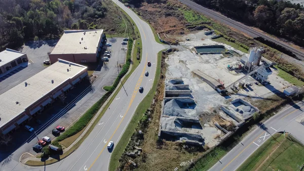 Ready-mixed concrete batching plant near strips mall highway in Flowery Branch, Georgia, USA. Aerial view cement silo, weigh hopper, conveyors, screw feeder, aggregates granular gravel, crushed stone