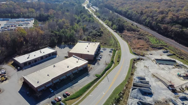 Aerial view strips mall in industrial zone with ready-mixed concrete batching plant, warehouse and highway in Georgia, USA. Cement silo, weigh hopper, conveyors, screw feeder, gravel, crushed stone