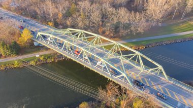 Aerial view truss bridge with car traffic over Erie Canal with colorful fall foliage in late afternoon light Pittsford, New York. The Pratt through bridge was originally built in 1973 State Route 96