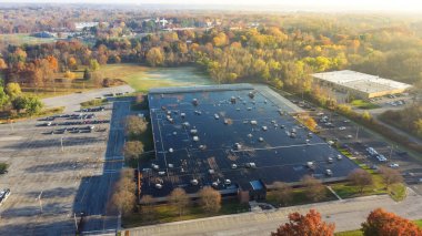 Large commercial building in woodland area with colorful fall foliage and rooftop units HVAC system provide heating, cooling, and ventilation in Pittsford, New York, USA. Aerial view industrial zone