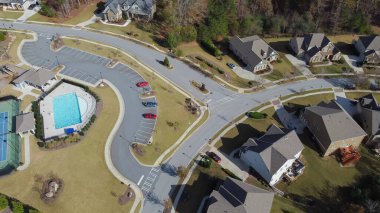 Two-story houses with grassy yards near community facility with swimming pool, tennis courts suburbs Atlanta, Georgia, USA. Upscale single-family home in woodland area shingle roofs and front garage