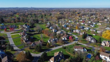 Aerial view master planned low density single family residential houses with grassy yards landscaping and Rochester Downtown buildings in far distance, Upstate New York, USA. Upscale two story home