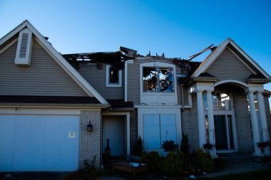 Front door garage of two-story single-family home with shingle roof ruined by fire in Rochester, New York, USA. Aftermath of destroyed residential home disaster for insurance claim concept