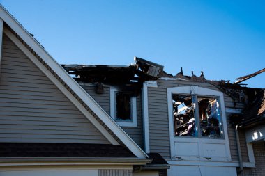 Broken windows on second floor and gable roof edges pitches of single-family home destroyed by fire in Rochester, New York, USA. Aftermath of wooden residential home disaster for insurance claim concept
