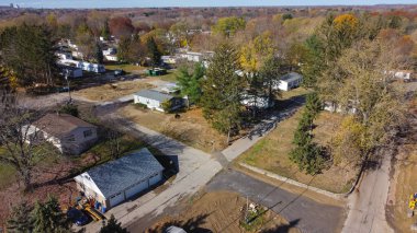 Trailer park with new development prefabricated houses at a low-income housing neighborhood in Rochester, Upstate New York, USA. Aerial view prefabricated modular home and colorful fall foliage
