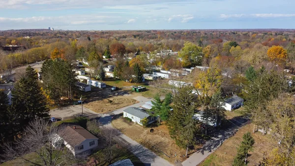 Aerial view mobile home park with Rochester downtown building in distance background, Upstate New York, USA. Low-income housing neighborhood with prefabricated modular house colorful autumn leaves