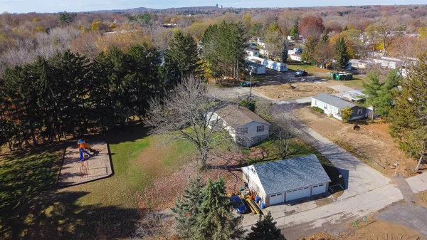 Aerial view mobile home park with Rochester downtown building in distance background, Upstate New York, USA. Low-income housing neighborhood with prefabricated modular house colorful autumn leaves