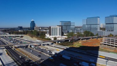 Modern transportation infrastructure Interstate 285 (the Perimeter), Skytrain railway, busy traffic, skylines midtown Atlanta background. Aerial view mixed-use developments Dunwoody, Georgia, US
