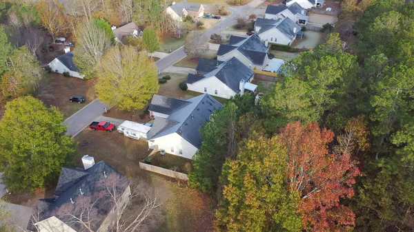 Light frost on shingle roofs of detached single family houses with lush greenery trees in an established subdivision near Hog Mountain Road, Flowery Branch, Georgia, USA. Aerial view suburban homes