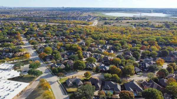 Lakeside master planned community urban sprawl mixed of single-family homes and apartment complex, downtown building distance background colorful fall leaves in North Texas, USA. Aerial subdivision