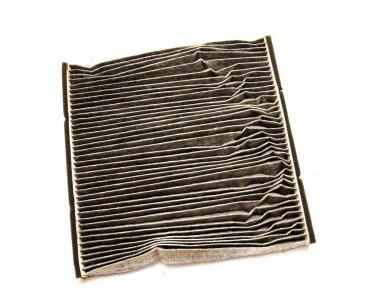 Üst kattaki kirli oto kabin hava filtresi beyaz zemin üzerinde izole edilmiş enkaz ve kirlenmiş hava akışı ile kaplı fiber kağıt pamuktan yapılmıştır. Değiştirilmiş hava filtresi