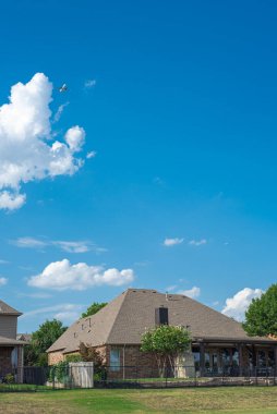 Bulutlu mavi gökyüzü arka planı olan, metal çitli, kiremitli çatısı olan, Teksas, Teksas 'taki çimenli çimlerin üzerinde uçan uçaklar. Güneşli bir gün