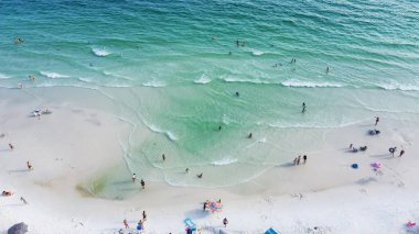 Gorgeous shade of blue and crystal-clear turquoise water of Santa Rosa beach, brilliantly white sandy shore with people swimming, relaxing laid-back vibe charming Walton County, Florida, USA. Aerial