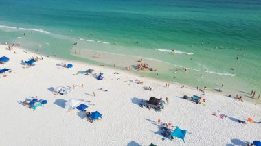 Güzel, beyaz kumlu plajlar ve bir sıra plaj şemsiyesi. Aile bireyleri toplanıyor, dinleniyor, turkuaz suda yüzüyor. Güney Walton, Florida, ABD 'de muhteşem mavi dalgalar. Hava görünümü