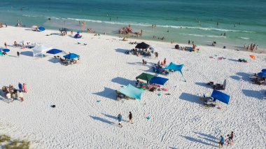Güzel, beyaz kumlu plajlar ve bir sıra plaj şemsiyesi. Aile bireyleri toplanıyor, dinleniyor, turkuaz suda yüzüyor. Güney Walton, Florida, ABD 'de muhteşem mavi dalgalar. Hava görünümü