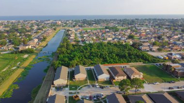 Waterfront Lake Pontchartrain neighborhood with row of townhomes, two-story single-family house, apartment complex along Farrar canal Lake Barrington, Little Woods, Eastern New Orleans. Aerial view clipart