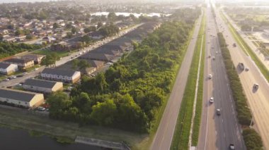 Sabah erken saatlerde Barrington Gölü yakınlarındaki 10 numaralı otobanda yoğun trafik var. Kasaba evleri, apartmanlar, yemyeşil ağaçlar ve Doğu New Orleans Little Woods 'taki yerleşim birimleri boyunca.