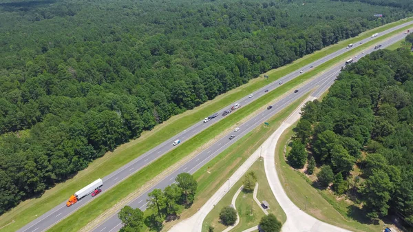 Busy traffic along highway interstate 10 (I-10) and exit of Greenwood rest area in Louisiana, surrounding lush green Loblolly pine Pinus taeda products forest industry site. Aerial freeway rest stop
