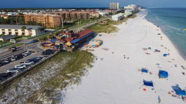 Şekerli beyaz kumlu sahil şeridi, renkli plaj şemsiyesi ve insanlar Miramar Sahili 'nde 98 Scenic Gulf Drive boyunca dinleniyorlar. Daire sırası, daire, tatil kiralama. Havadan kumsal topluluğu