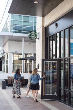 PLANO, TX, ABD-AUG 18, 2023: Plano, Teksas, Amerika 'da bulunan Legacy West' teki Starbucks Reserve kahve dükkanına giren çeşitli kadın müşteriler. Nadir, sıra dışı kahve seçimleri Starbucks