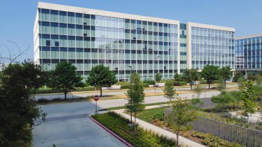 Group of glass office building with nice landscaping and outdoor recreation yard in business center downtown Plano, Texas, USA. Aerial view modern corporate towers in Dallas Fort Worth metro complex clipart