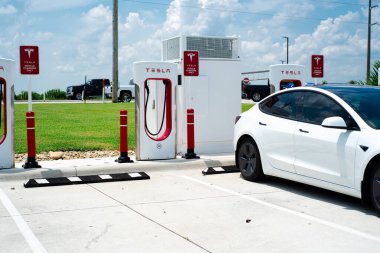 Robertsdale, AL, US-JUL 27, 2023: Tesla Model 3, büyük benzin istasyonu otoparkında sıcak yaz günü şarj ediliyor. Yüksek voltajlı doğrudan DC hızlı şarj şebekesi