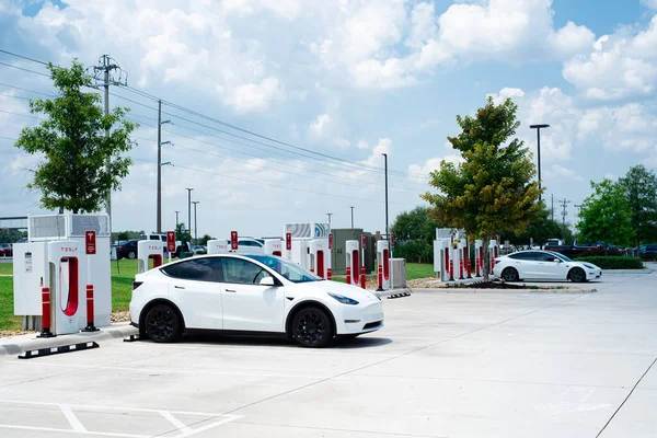 Robertsdale, AL, US-JUL 27, 2023: Tesla Model 3, güneşli mavi gökyüzü gününde Tesla Supercharger İstasyonu 'nda şarj oluyor. Yüksek voltajlı doğrudan DC hızlı şarj şebekesi