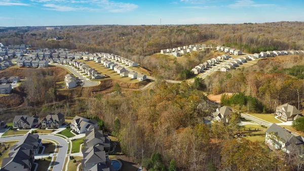Master planned community row of new development two-story houses in lush green trees area, urban sprawl to horizontal line suburb Atlanta, Georgia, USA aerial view. Upper middle-class real estate
