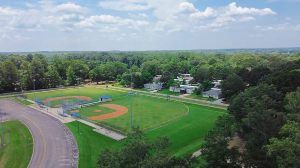Baseball park complex near mobile trailer home residential neighborhood in Richland, suburb of Jackson Mississippi, USA surrounding by lush green trees. Aerial view community recreation facility