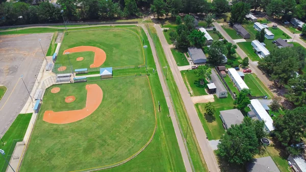 Baseball park complex near mobile trailer home residential neighborhood in Richland, suburb of Jackson Mississippi, USA surrounding by lush green trees. Aerial view community recreation facility