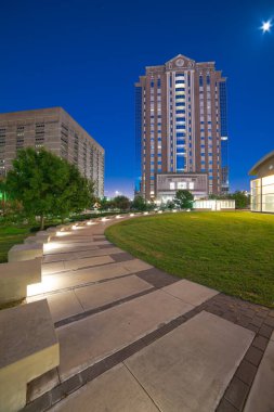 Houston belediye mahkemeleri parkın meydanında beton kaldırımlar, şehir merkezindeki gökdelenler, akşam saatlerinde ofis binaları. Modern yüksek binalar metro kompleksinde iş birliği yapıyor