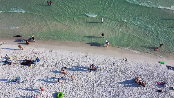 Yüzen, şekerli beyaz kumlu sahil şeridinde dinlenen, turkuaz su, Güney Walton plajı, Destin, Florida, ABD, renkli çadırlar, gölgelik, plaj şezlongları. Seyahat hedefi