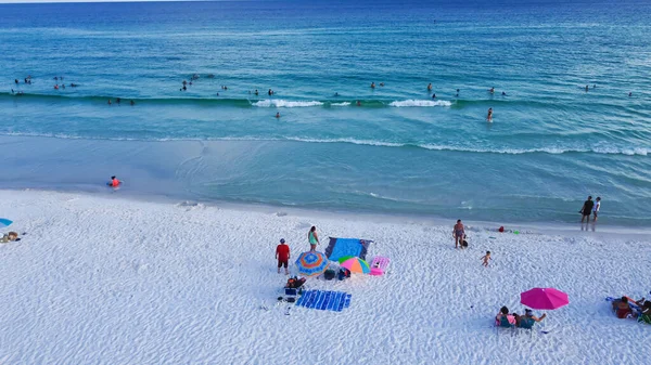 Miramar Sahili, beyaz kumlu sahil şeridi, turkuaz suyu, mavi dalgalar ve yüzen, rahatlatan, renkli çadırları olan bir sürü insan, tente, şezlong sandalyesi, Destin, Florida. Seyahat hedefi