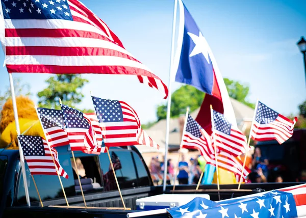 Dense of Texas and American flags on cargo bed of modern pickup truck driving on residential street smalltown Fourth of July parade, Dallas, Texas, USA blurry diverse people. Independence Day patriot