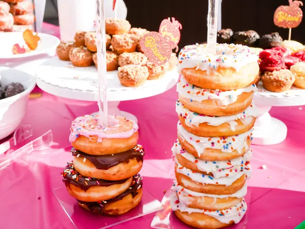 Stack of icing sprinkle, chocolate glazed donuts, cookies on outdoor party feast table at Thanksgiving event in Dallas, Texas, USA, treat sugar dessert holiday season. Doughnut collection variety