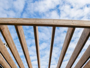 Duvarda kumlu pergola çatı kirişleri mavi bulut gökyüzü arka planıyla yeniden boyanmaya hazır ahşap kirişler kereste sonrası dış yapı yapı bahçesi Dallas, Teksas, doğal ahşap tahıl. DYI projesi