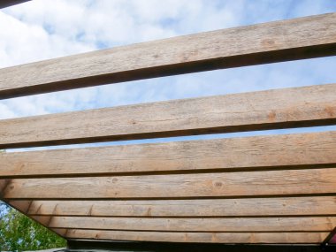 Kumlu pergola çatı kirişleri mavi bulut gökyüzü arka planıyla yeniden boyanmaya hazır, ahşap kirişler kereste kaplamalı dış yapı bahçesi Dallas, Teksas, ABD, doğal ahşap tahıl. DYI projesi
