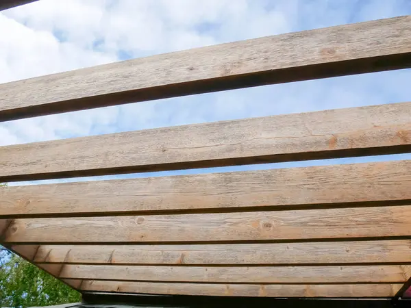 Kumlu pergola çatı kirişleri mavi bulut gökyüzü arka planıyla yeniden boyanmaya hazır, ahşap kirişler kereste kaplamalı dış yapı bahçesi Dallas, Teksas, ABD, doğal ahşap tahıl. DYI projesi