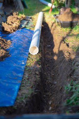 Plastik kanalizasyon boruları PVC, kirli mavi muşamba, siyah karıştırma kabı, döşemeye hazır boru, yağmur suyu drenajı için toprak çukuruna gömülmüş ev, Dallas, Teksas, ABD. Kanalizasyon borusu