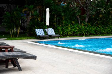Çökmüş beyaz plaj şemsiyesi ve havuz başında şezlonglu şezlong şezlong, teras rahat koltuklar, tropikal bahçe, Nha Trang, Vietnam 'da 5 yıldızlı otel. Seyahat arkaplanı